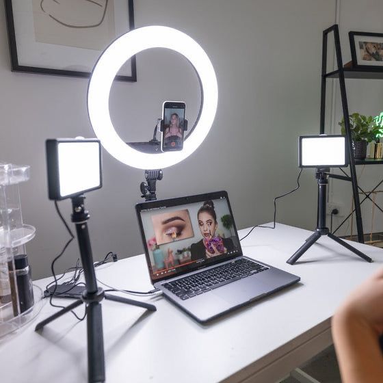 a laptop computer sitting on top of a desk next to a camera and light fixture