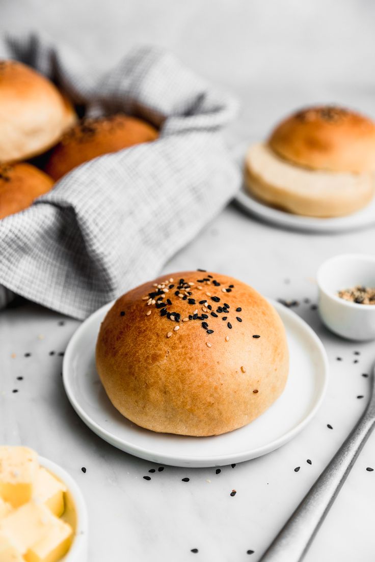 bread rolls and butter sit on plates next to small bowls with dips in them