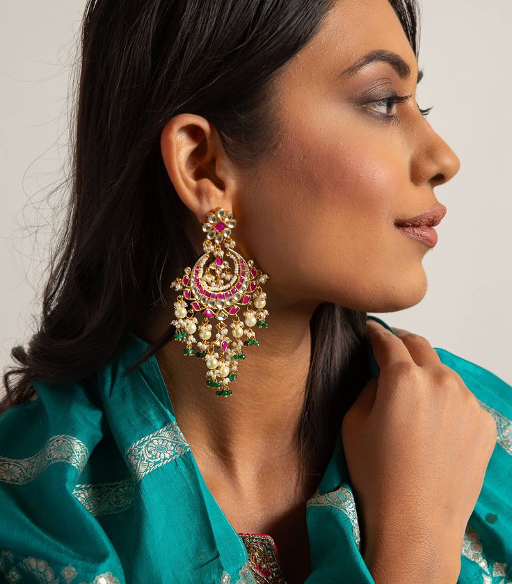 Step into refined elegance with the Nishi red & green kundan chandbali, a captivating blend of vibrant colors and exquisite craftsmanship. These chandbalis feature radiant red and green kundan stones, beautifully set in intricate gold detailing that enhances their allure. Perfect for festive occasions, they add a touch of regal charm to your look, ensuring you stand out with every elegant sway. Kundan Chandbali, Radiant Red, Ethnic Design, Green Onyx, Photographic Lighting, Gold Details, Modern Woman, Red Green, Vibrant Colors