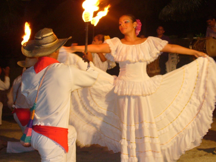 two people dressed in white dancing with torches