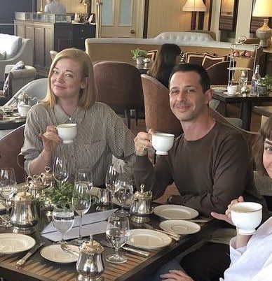 a group of people sitting at a table with cups and saucers in their hands