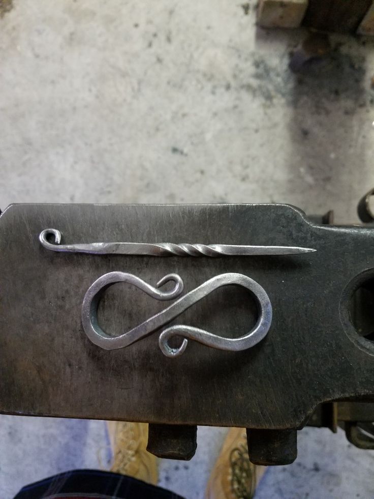 a metal object with an infinite sign on it's side and a pair of scissors in the middle