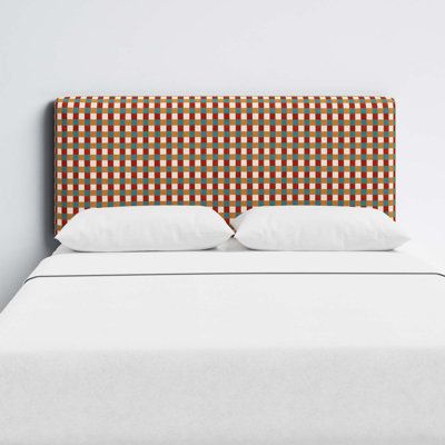 an upholstered headboard on a bed with white linens and brown checkered fabric