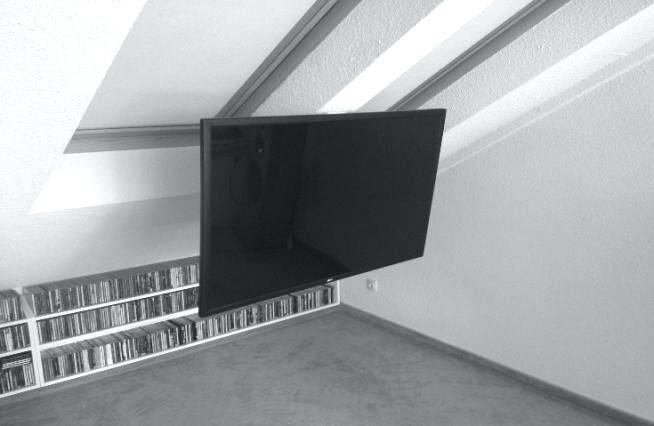 a flat screen tv mounted to the side of a wall next to a book shelf