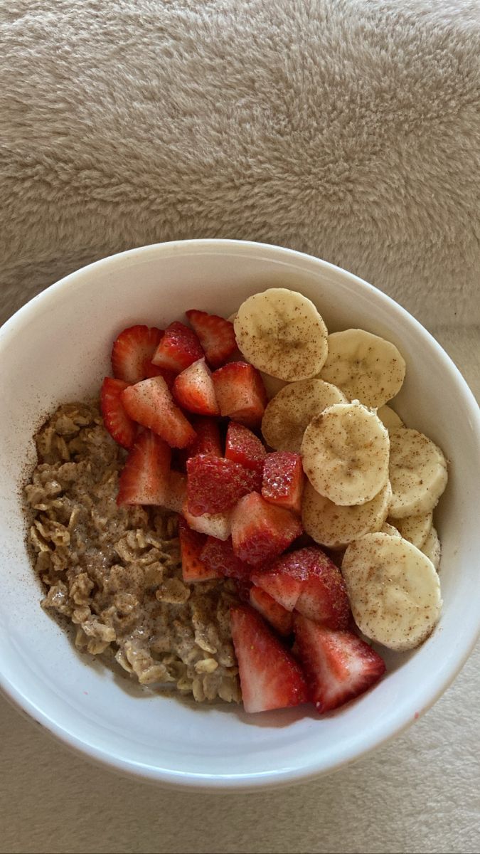 a white bowl filled with oatmeal and sliced banana's on top