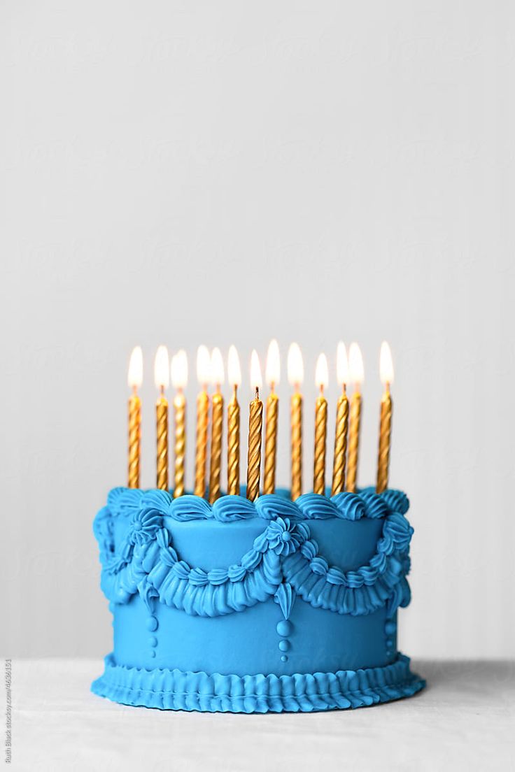 a blue birthday cake with lit candles on it