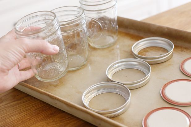 a person is placing mason jars on a tray with other items in the bottom half