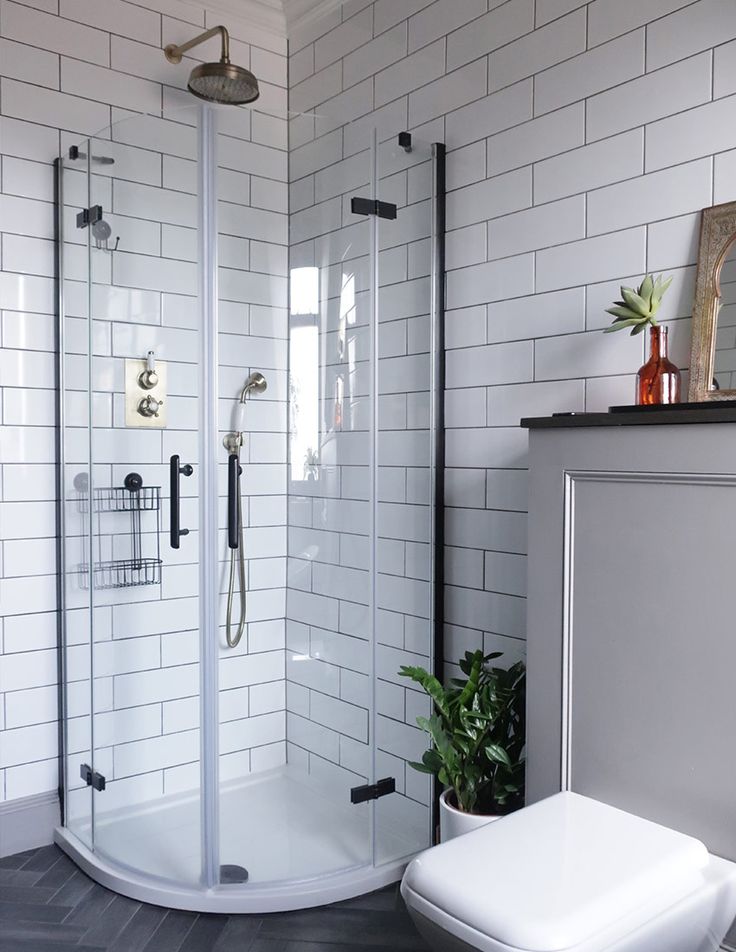 a bathroom with a toilet, shower and tiled walls