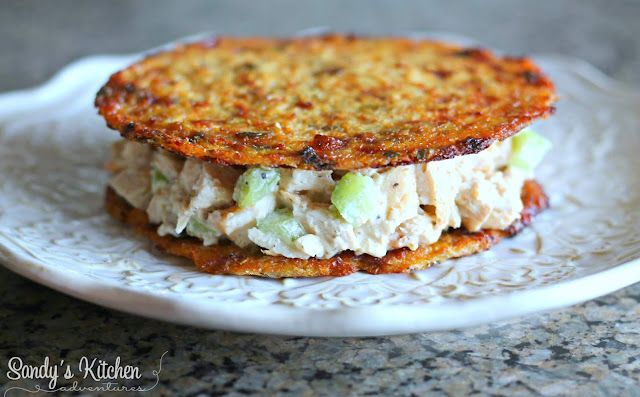 a chicken salad sandwich is on a white plate and sits on a granite countertop