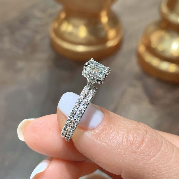 a close up of a person's hand holding a diamond ring