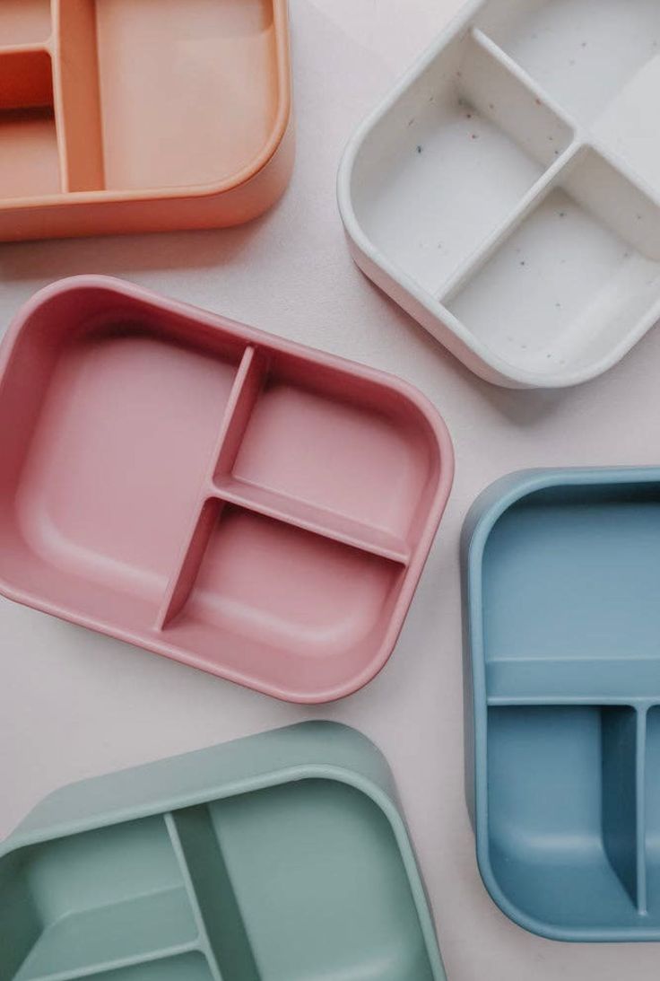 four different colored trays on a white surface