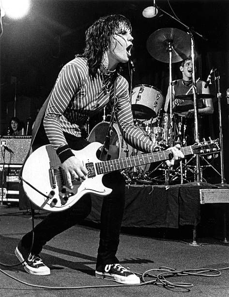 an image of a man playing guitar in front of microphones and drums on stage