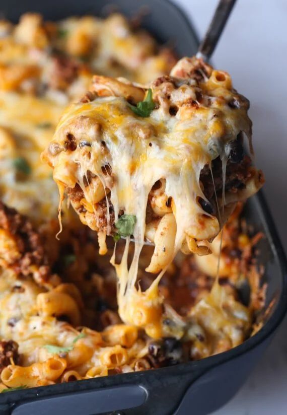 a close up of a casserole dish with cheese and ground beef being lifted from the casserole