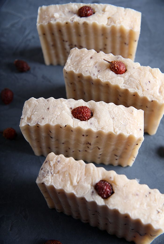 three bars of soap with raspberries on them sitting next to some raisins