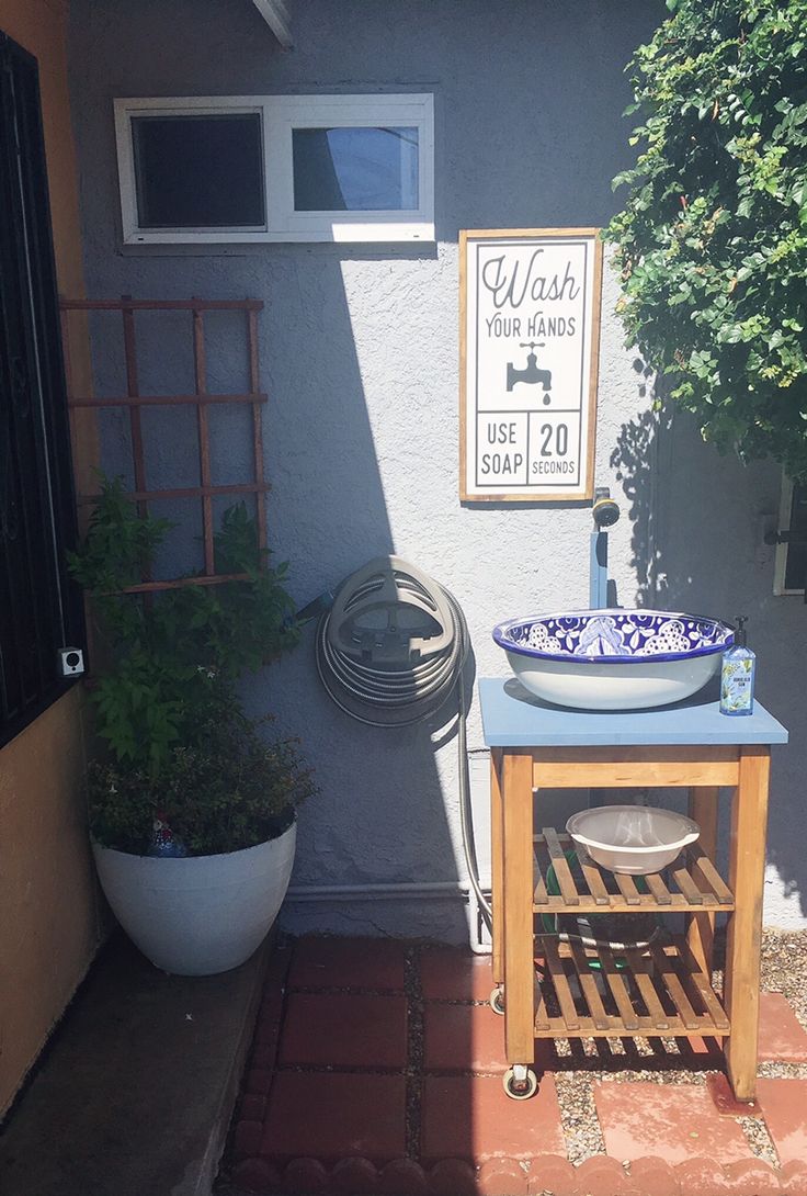 the outside of a house with a sink and potted plants