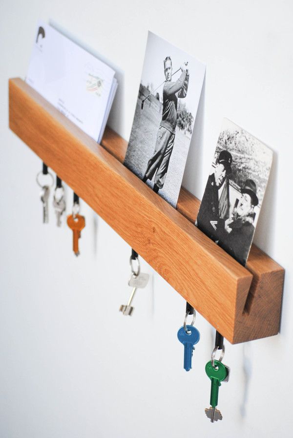 a wooden shelf with keys hanging from it's sides and pictures on the hooks