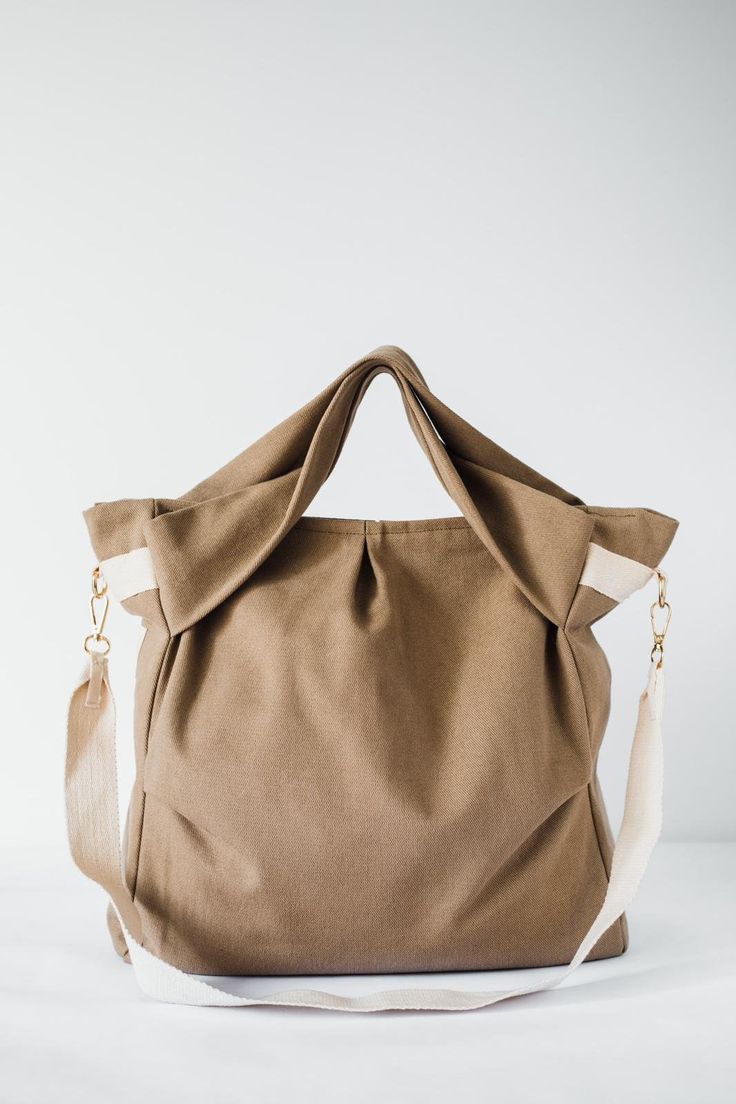 Discover the refined elegance of our Cocoon Bag, the perfect blend of style and functionality for the modern woman. This unique khaki fabric bag is not just an accessory; it is a sophisticated statement and a testament to artisanal craftsmanship.  👜 Exceptional Quality: Each bag is carefully crafted from high quality, durable khaki fabric that ensures longevity and durability for everyday use. 🌿 Eco-Friendly Material: Dedicated to sustainability, our cocoon bag is crafted with environmentally conscious fabrics that contribute to a greener planet. 🤲 Handmade Excellence: Artisans with years of experience meticulously create each bag with impeccable stitching, flawless construction and attention to detail. 👝 Versatile Style: The neutral khaki hue and classic design make it a versatile add Chic Taupe Bucket Bag For Everyday, Chic Olive Shoulder Bag, Travel Tote Hobo Bag In Khaki, Khaki Tote Satchel For Everyday, Travel Khaki Hobo Tote Bag, Travel Khaki Hobo Bag Tote, Versatile Khaki Shoulder Bag For On-the-go, Khaki Canvas Satchel With Removable Pouch, Modern Khaki Tote Bag