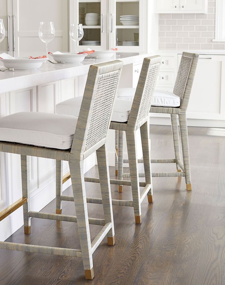 a kitchen with white counter tops and chairs in front of a bar stool that has beige upholstered backrests