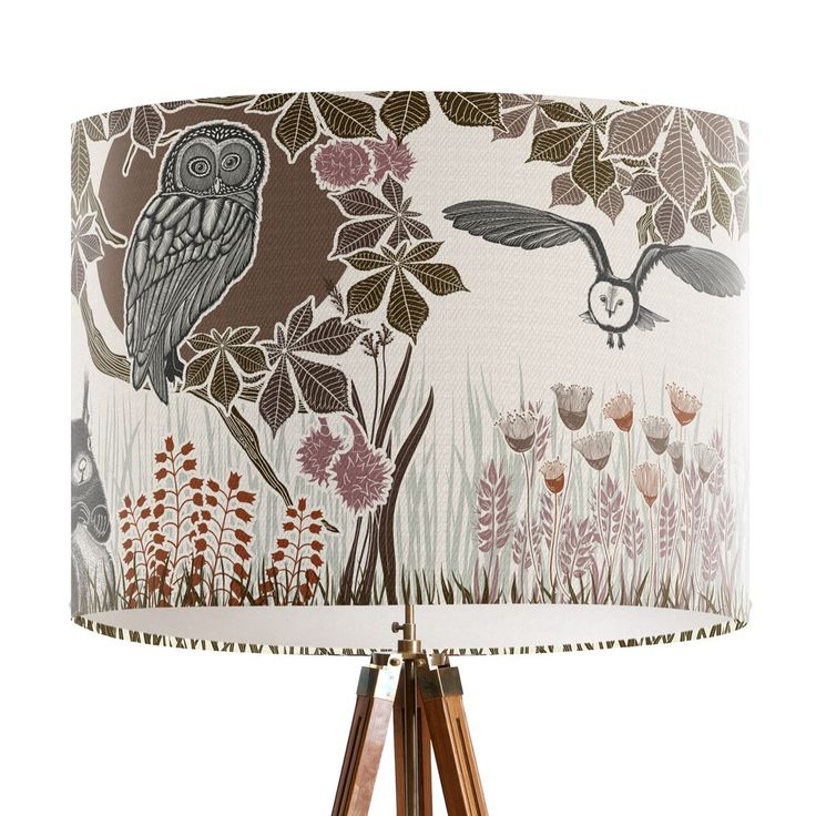 a lamp with an owl design on it and wooden tripod lampshade in the background