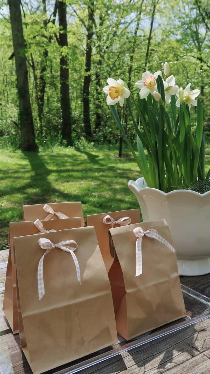 three brown paper bags sitting on top of a table next to a vase filled with flowers