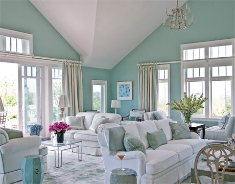 a living room filled with white furniture and lots of windows on top of it's walls