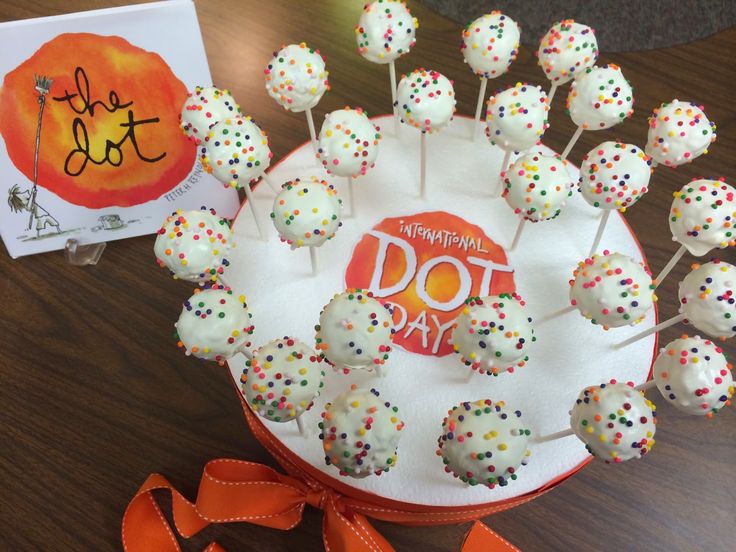 cake pops with sprinkles are arranged on a table next to an orange ribbon