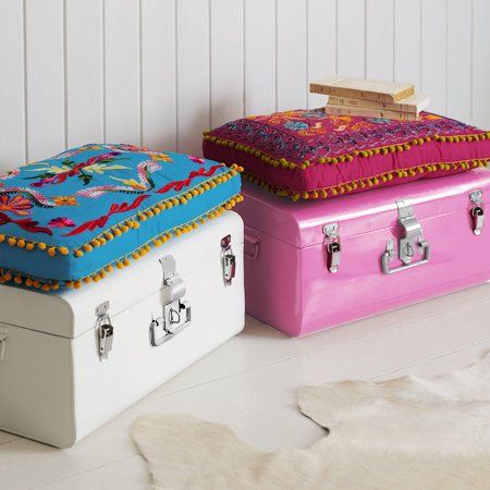 two colorful suitcases sitting next to each other on a white floor and one has a cushion