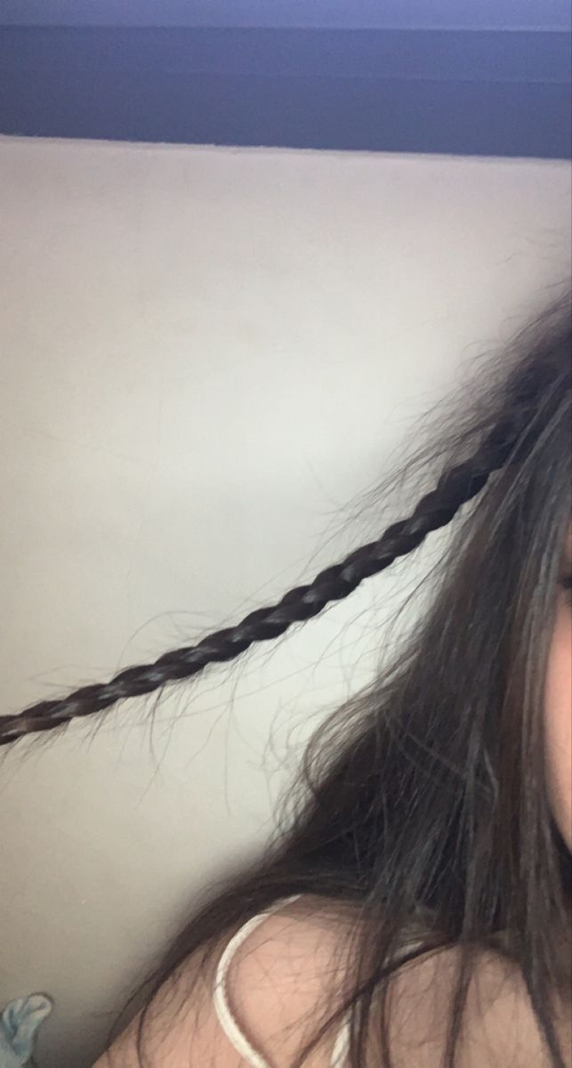 a close up of a person with long hair and an object in her hand behind her head