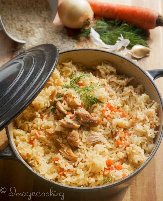 a pot filled with rice and carrots on top of a wooden table