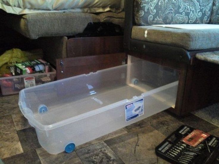 an empty plastic container sitting on the floor next to a bed and other items in boxes