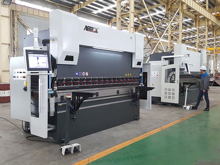 two men are standing in front of large machines that are being used for cutting sheet metal