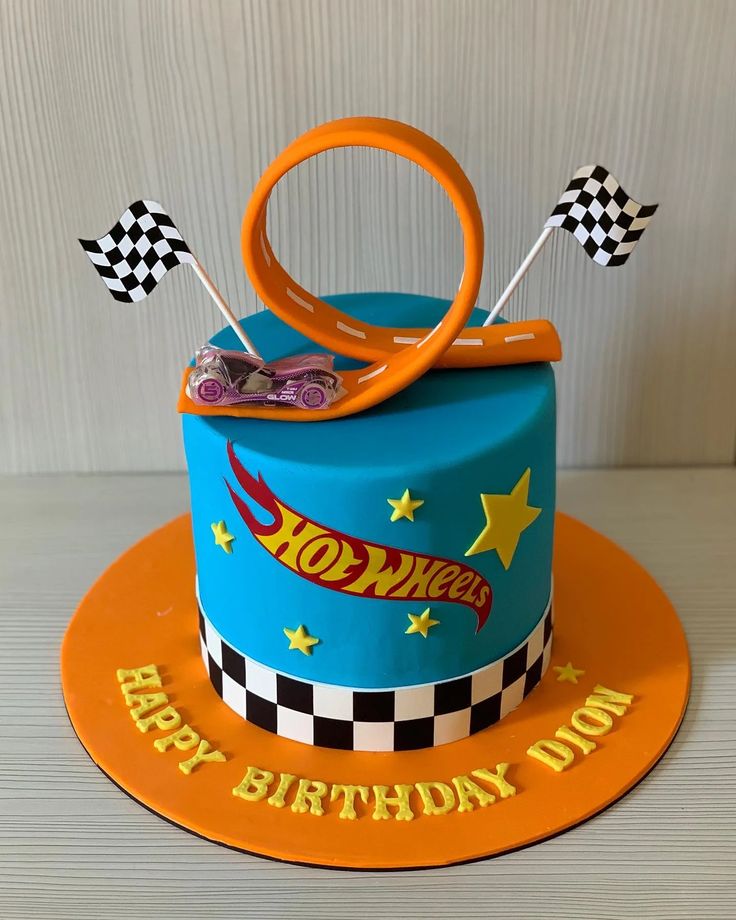 a birthday cake that is decorated with a hot wheels theme and some scissors on top