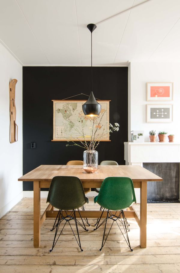 a dining room table with green chairs and a painting on the wall in the background