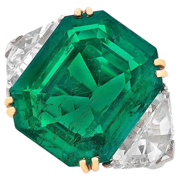 This exquisite ring features a ICA Certified 7.37 carat vivid green emerald as its stunning centerpiece, radiating a rich and captivating hue. Flanking the emerald are two shield-cut diamonds, adding a touch of brilliance and enhancing the ring's luxurious appeal. The emerald is set in an 18k white and yellow gold mounting, providing a perfect contrast that accentuates the vivid green of the gemstone. This ring combines exceptional craftsmanship with elegant design, making it a remarkable additi Luxury Fine Jewelry With Emerald, Luxury Green Diamond Gemstone Ring, Luxury Green Diamond Ring With Polished Finish, Luxury Green Diamond Cut Rings, Luxury Green Emerald Cut Jewelry, Luxury Fine Jewelry Emerald Ring With Vvs Clarity, Luxury Emerald Cut Green Jewelry, Luxury Green Ceremonial Rings, Luxury Modern Green Ring