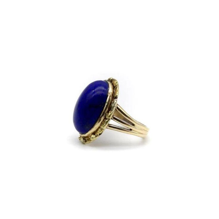 This is part of Chairish’s Fine Jewelry assortment.  A vivid blue lapis cabochon is bezel set into a halo of 22k gold nuggets. The stone is a deep, well-saturated cobalt blue, while the gold nuggets bring richness and texture to the surface of the ring. The effect is stunning, and the two elements compliment each other beautifully. The 14k gold band splits into three, adding a hint of drama and elegantly framing the lapis centrepiece. A bold cocktail ring, true blue!  This type of nugget work ar Gold Domed Gemstone Cabochons, Domed Gold Gemstone Cabochons, Classic Blue Gemstone Cabochons, Classic Blue Domed Jewelry, Blue Domed Jewelry With Polished Finish, Polished Yellow Gold Oval Cabochon Gemstones, Yellow Gold Polished Oval Cabochon Gemstones, Blue Domed Cabochon Jewelry, Yellow Gold Oval Cabochon Gemstone With Polished Finish