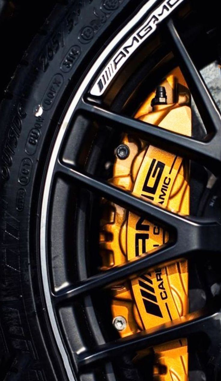 the front wheel of a car with yellow brake pads and black rims on it