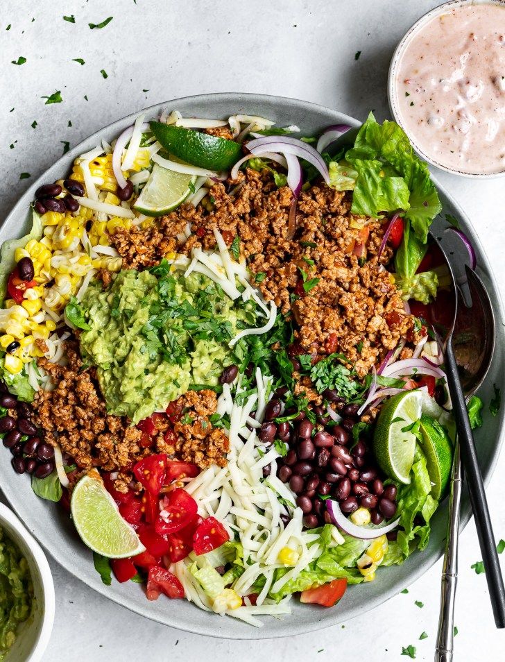 a salad with black beans, lettuce, avocado and other toppings