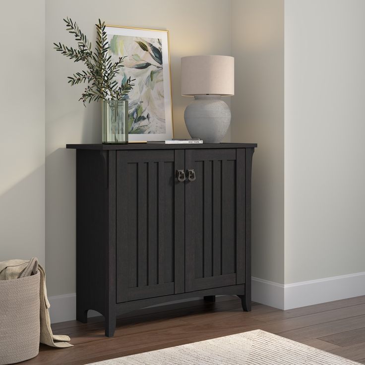 a black cabinet sitting on top of a hard wood floor next to a white vase