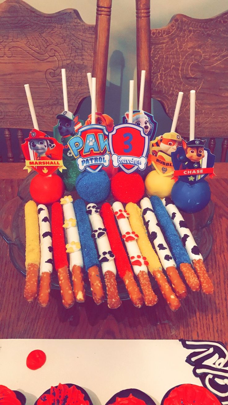 an arrangement of cupcakes and candy on a table in front of a wooden chair