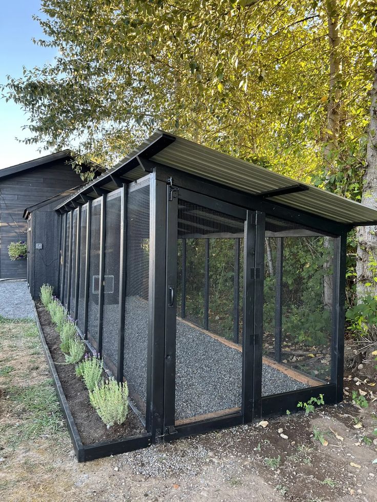 a small black building sitting in the middle of a field next to some trees and grass