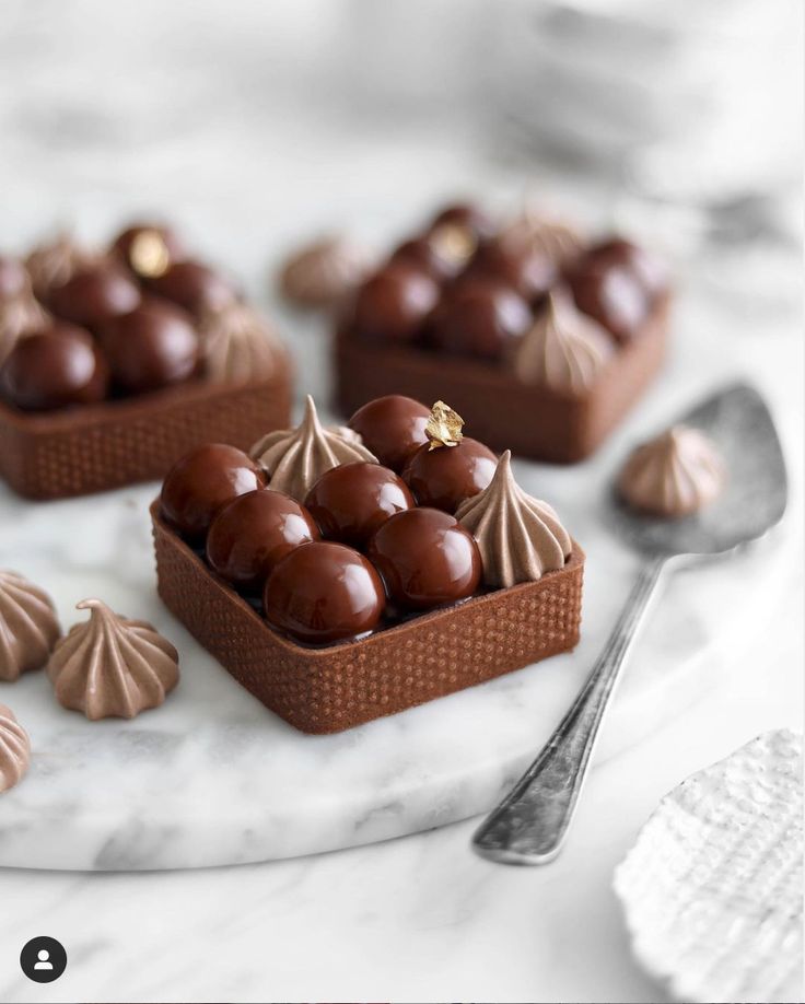 some chocolates are sitting on a white plate with spoon and fork next to them