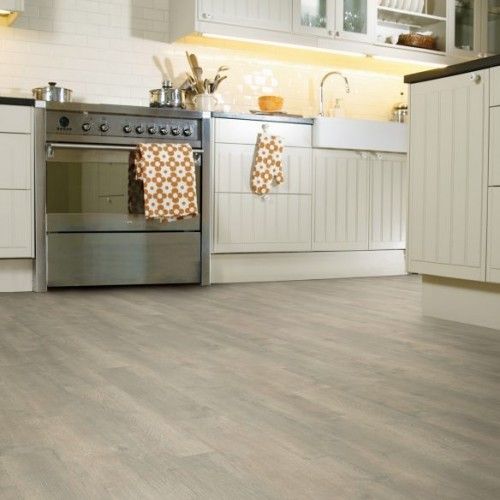 a kitchen with white cabinets and beige tile flooring, including an oven in the center