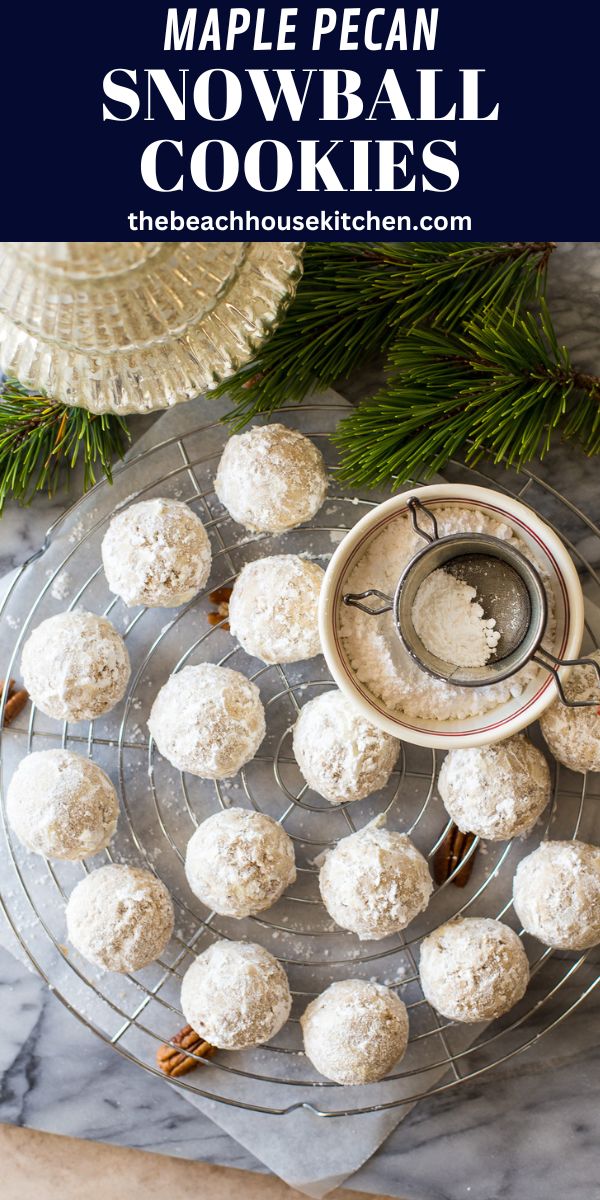 snowball cookies on a plate next to pine branches and a bowl with powdered sugar