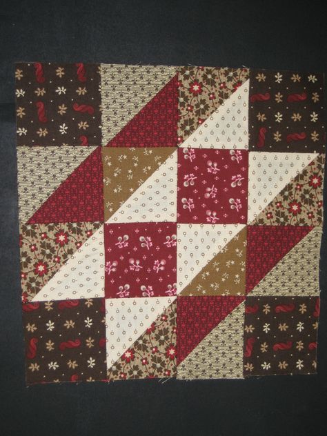 a patchwork quilt with red, brown and white squares on it's sides