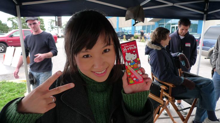 a young woman holding up a box of hello kitty crackers in front of her face