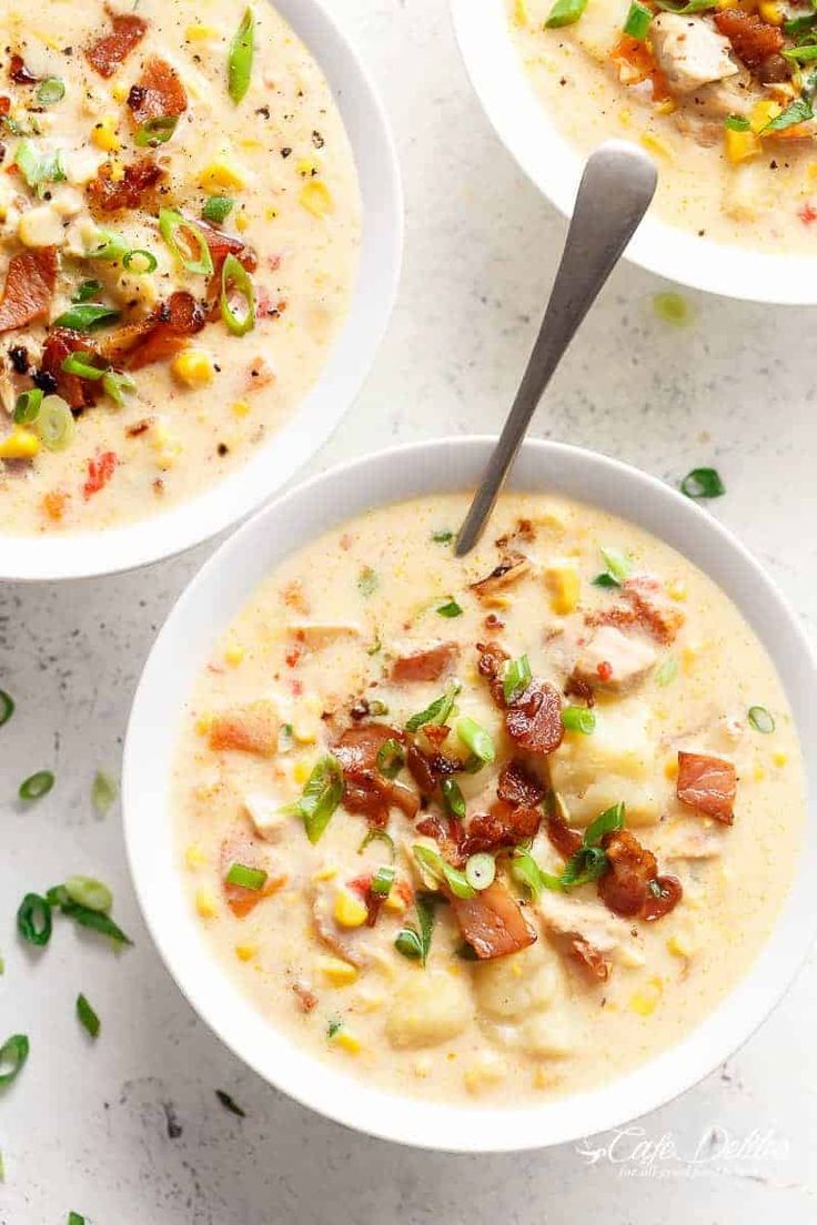 three white bowls filled with soup and topped with bacon, green onions, and cheese