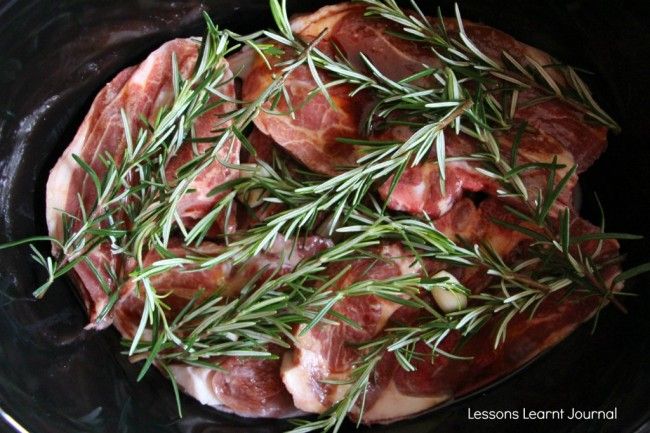 raw meat in a skillet with rosemary sprigs