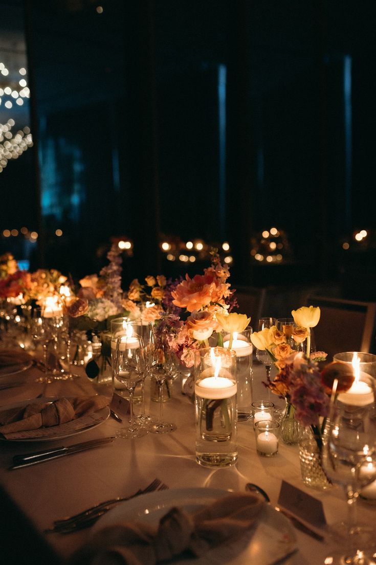 a long table is set with candles and flowers in glass vases on the tables