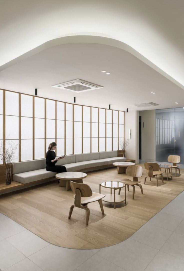 a person sitting on a bench in a room with wooden tables and chairs around it