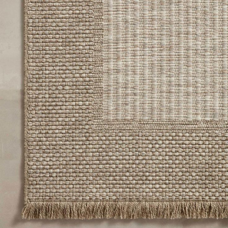 a beige rug with fringes on the floor